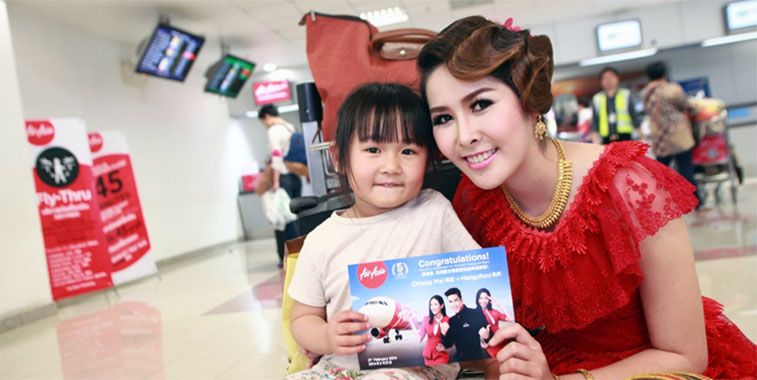 A Thai AirAsia crew member presents a young passenger with an inaugural flight ticket.